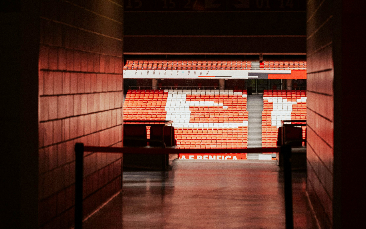 Dark hallway leading to a stadium with rows of empty red and white seats