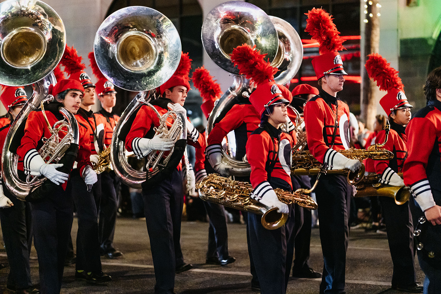 A high school marching band performs on a grass field during a sporting event